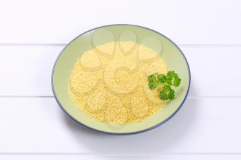 plate of raw couscous on white wooden background