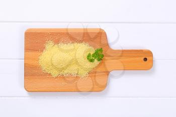 pile of raw couscous on wooden cutting board