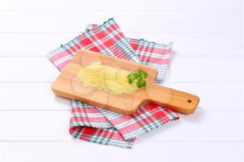 pile of raw couscous on wooden cutting board