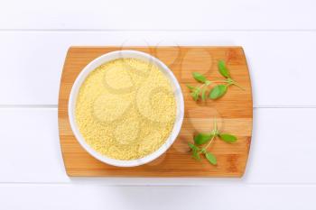 bowl of raw couscous on wooden cutting board
