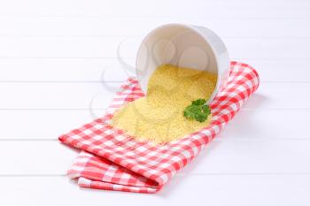 bowl of raw couscous spilt out on checkered place mat