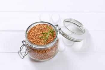 jar of raw buckwheat on white wooden background