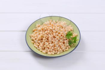 plate of canned white beans on white wooden background