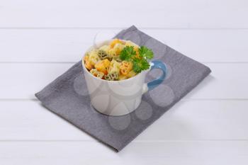 mug of cooked colored pasta on grey place mat