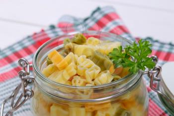 jar of cooked colored pasta on checkered place mat - close up