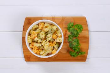 bowl of cooked colored pasta on wooden cutting board