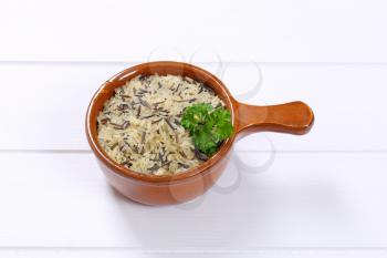 saucepan of wild rice on white wooden background
