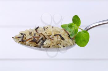 spoon of wild rice on white wooden background