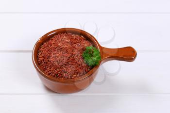 saucepan of red rice on white wooden background