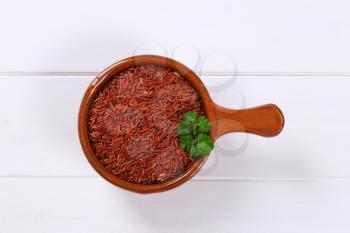 saucepan of red rice on white wooden background