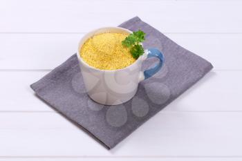 mug of raw millet on grey place mat