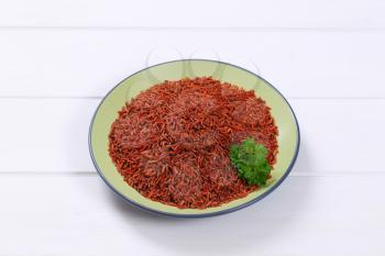 plate of red rice on white wooden background