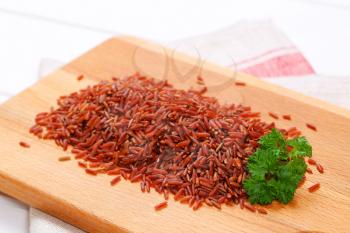 pile of red rice on wooden cutting board - close up
