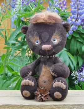 Handmade, the sewed toy: teddy-bear Mocca on a little board among flowers lupine and buttercups