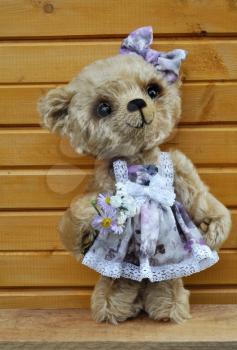 Handmade, the sewed toy: teddy bear Lucky before a wooden wall