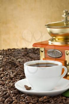 cup of coffee and grinder with roasted beans