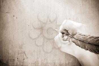 writing hand with pen feather on sepia