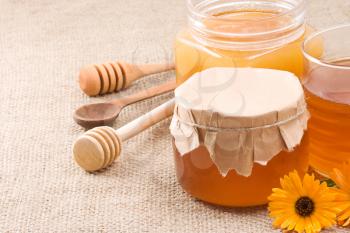 glass pot with honey on sacking