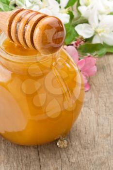 honey in glass jar and  stick on wood