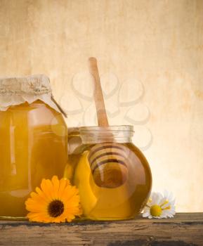 glass jar of honey and stick on wood background