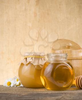 glass jar full of honey and stick on wood background