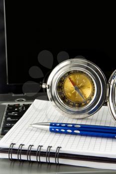 pen and gold compass on notebook laptop