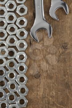 metal nuts and wrench tool on wood background texture