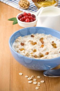 Bowl of oatmeal with berry and milk on wood