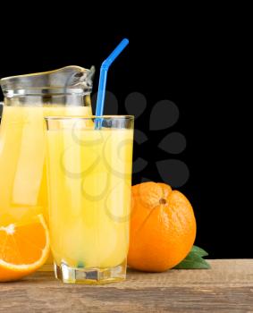 orange juice in glass and jug isolated on black background
