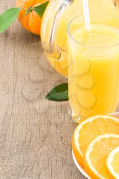 orange juice in glass and slices on wood background