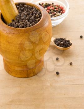 pepper spices and mortar with pestle on wooden texture
