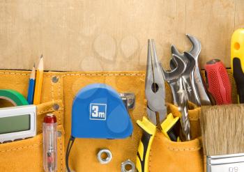 tools in construction belt on wooden background texture