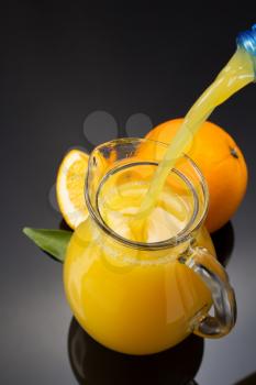 glass pitcher and orange juice on black background