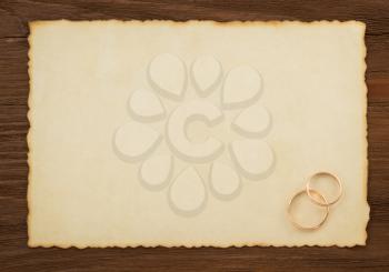 wedding ring and aged paper on wood background