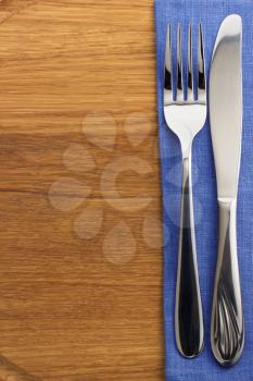 knife and fork at napkin on wooden board