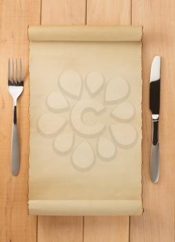 parchment and fork with knife on wooden background