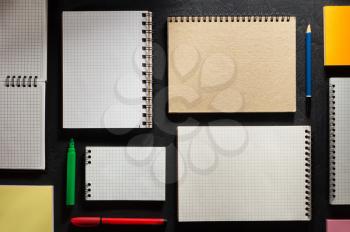 school supplies and notebook on black background