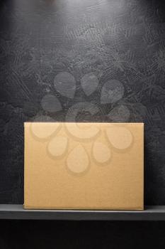 cardboard box on wooden shelf black background surface
