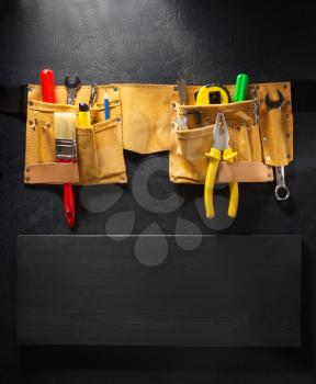 tools and instruments in belt on black background