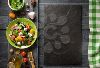 fresh greek salad in plate and ingredients on wooden table