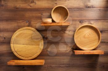 wooden kitchenware at shelf on brown background