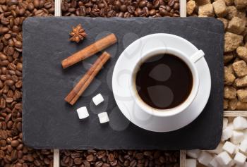 cup of coffee and beans on slate stone black tray background, top view