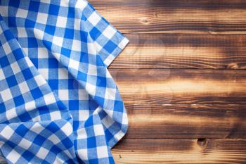 checked cloth napkin or tablecloth at rustic wooden plank board table background, top view