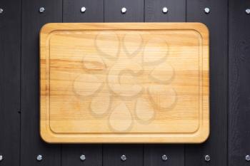 cutting board at rustic wooden plank board background, top view