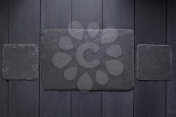 slate stone nameplate or wall sign at black wooden background texture surface, with screws