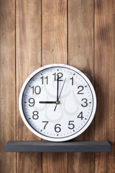 wall clock at shelf on wooden background texture