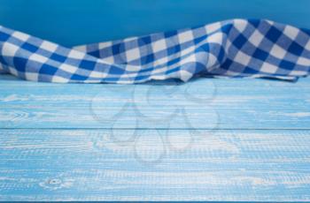 cloth napkin at blue rustic table in front, wooden plank board background