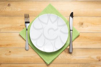 plate, knife and fork at rustic wooden plank board table background, top view
