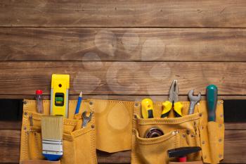 instruments in tool belt at wooden table surface background