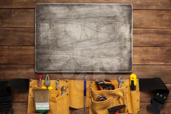 instruments in tool belt at wooden table surface background